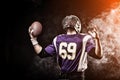 American football player holding ball in his hands in smoke. Black background, copy space. The concept of American Royalty Free Stock Photo