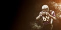 American football player holding ball in his hands in smoke. Black background, copy space. The concept of American Royalty Free Stock Photo