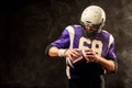 American football player holding ball in his hands in smoke. Black background, copy space. The concept of American Royalty Free Stock Photo