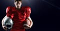 American football player holding helmet and ball against black background Royalty Free Stock Photo