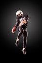 American football player in a jump with a ball on a black background Royalty Free Stock Photo
