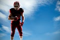 Composite image of american football player standing with rugby ball and helmet Royalty Free Stock Photo