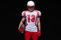 American football player wearing helmet posing with ball on black background Royalty Free Stock Photo