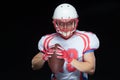 American football player wearing helmet posing with ball on black background Royalty Free Stock Photo