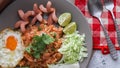 American fried rice served with sausages, cucumbers, shredded vegetables in a gray plate on a white table with seasoning Royalty Free Stock Photo