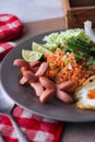 American fried rice served with sausages, cucumbers, shredded vegetables in a gray plate on a white table with seasoning Royalty Free Stock Photo