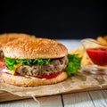 American hamburger with beef, french fries and tomato sauce on dark background. Royalty Free Stock Photo