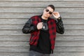 American handsome hipster fashionable man with stylish haircut in sunglasses in a trendy black t-shirt in a plaid jacket