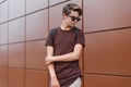 American hipster young man with a fashionable hairstyle in sunglasses in fashionable clothes with a black backpack poses Royalty Free Stock Photo