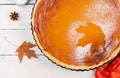 American homemade pumpkin pie with cinnamon and nutmeg, pumpkin seeds and autumn leaves