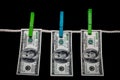 American hundred dollar bills hang on a rope with clothespins against a black background. Royalty Free Stock Photo