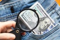 American hundred dollars sticking out of a hole in jeans close up magnified with a magnifying glass for reading Royalty Free Stock Photo