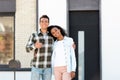 American husband and wife standing near new house and looking at camera while man showing thumb up Royalty Free Stock Photo