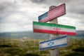 American, iranian and israelian national flags painted on wooden rustic signpost outdoors