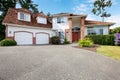 American large white house with two garage dors, red door and brick columns.