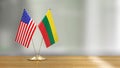 American and Lithuanian flag pair on a desk over defocused background