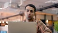 An American male teacher uses a laptop computer to chat with a friend. to be reviewing to prepare to teach students and in the