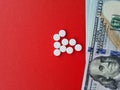 American one hundred dollar bills and pills on red background Royalty Free Stock Photo