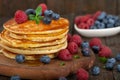 American pancakes with fresh blueberry, raspberry and honey served on wooden board Royalty Free Stock Photo