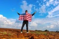 American, a patriot of the country, with the USA flag on his shoulders raised his hands to the blue sky with clouds. Love to USA Royalty Free Stock Photo