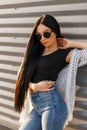 American pretty sexy young hipster woman in sunglasses with long hair in a stylish T-shirt in a summer jacket in trendy jeans Royalty Free Stock Photo