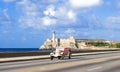 American rose convertible vintage car on the Malecon and in the background the Castillo de los Tres Reyes del Morro in Havana City