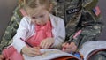 American servicewoman drawing together daughter in coloring book, parent care