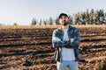 Young latin farmer man with crossed arms in the middle of the farmland. Agricultural sustainability concept.