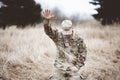 American soldier kneeling in despair on a grass field with his hand raised above