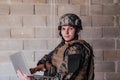 American soldier in military uniform using laptop computer for drone controlling and to stay in contact with friends and Royalty Free Stock Photo