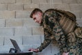 American soldier in military uniform using laptop computer for drone controlling and to stay in contact with friends and Royalty Free Stock Photo