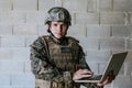 American soldier in military uniform using laptop computer for drone controlling and to stay in contact with friends and Royalty Free Stock Photo