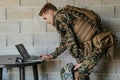 American soldier in military uniform using laptop computer for drone controlling and to stay in contact with friends and Royalty Free Stock Photo