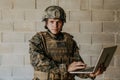 American soldier in military uniform using laptop computer for drone controlling and to stay in contact with friends and Royalty Free Stock Photo