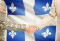 USA military man in uniform and civil man in suit shaking hands with certain Canadian province flag on background - Quebec