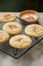 American style round cookies with confetti (shortbread) on a wire rack on a grey stone backdrop.