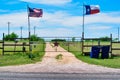 American and Texas state flags flying near countryside gate, Texas rustic star with road to the house slowly dissolving in the bac