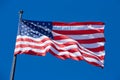 American or USA flag in wind with flagpole on blue sky Royalty Free Stock Photo