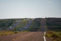 American view of an endless straight road running through the barren scenery of the Southwest.