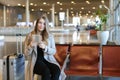 American woman using internet by tablet in airport hall near valise. Royalty Free Stock Photo