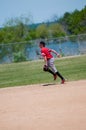 Teenage baseball shortstop running on field.