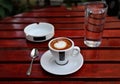 americano cup on saucer with spoon, ashtray, glass of water on red wooden coffee shop table (espresso, milk cappuccino) Royalty Free Stock Photo