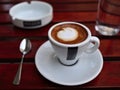 americano cup on saucer with spoon, ashtray, glass of water on red wooden coffee shop table (espresso, milk cappuccino) Royalty Free Stock Photo