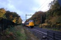 Amersfoort, the Netherlands, Nov 1,2020:Dutch yellow intercity passes in autumn scene with orange leaves on the trees