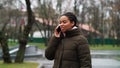 Amiable black girl talking on phone in park in cold weather