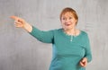 Amiable elderly woman in teal jumper pointing towards Royalty Free Stock Photo