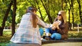 Amiable girls using smartphone apps sitting in autumn park