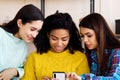 Amiable multiracial girls browsing social media using smartphone at home