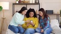 Amiable multiracial girls browsing social media using smartphone at home