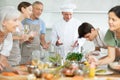 Smiling chef sharing secrets of cooking during culinary courses